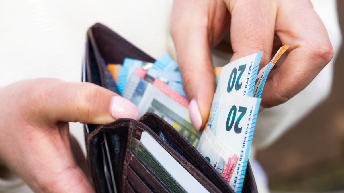 Macro image as a woman takes Euro banknotes from a leather wallet.