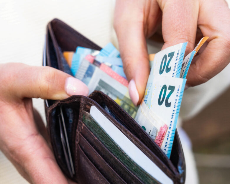 Macro image as a woman takes Euro banknotes from a leather wallet.
