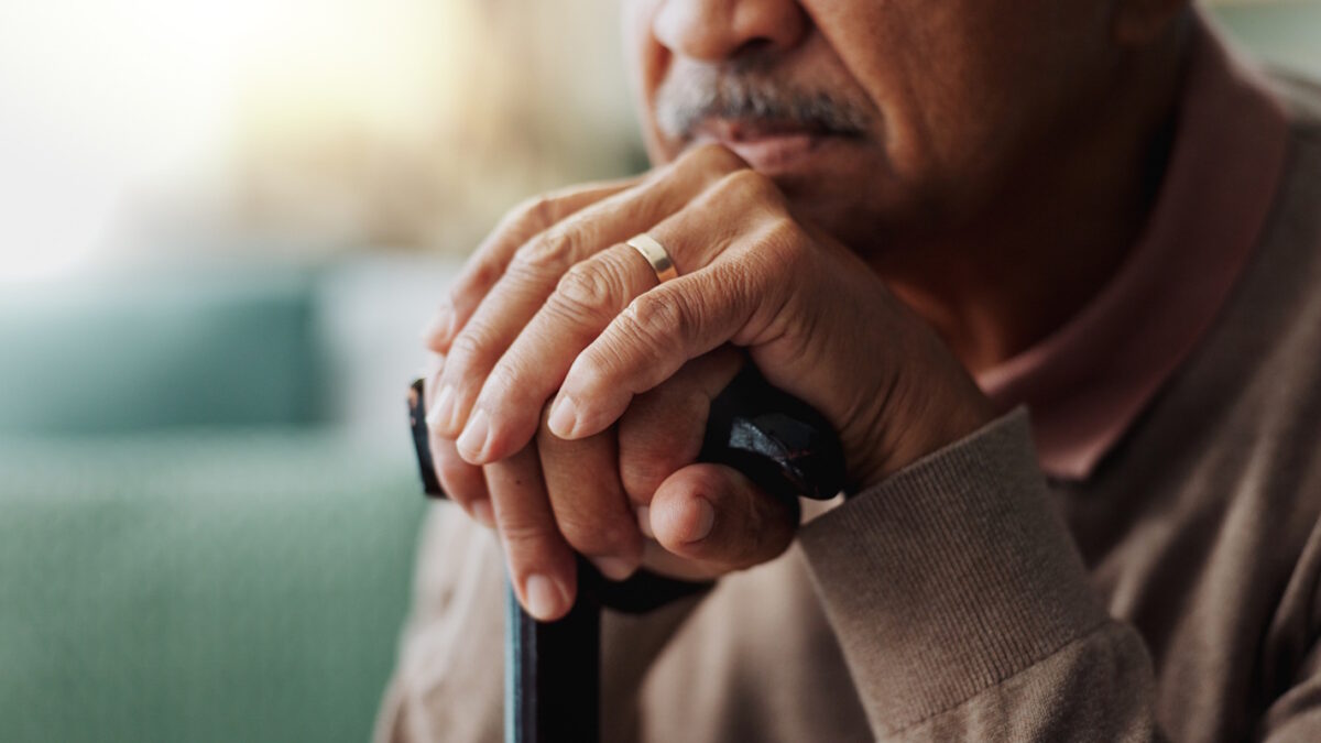Old man, hands and walking stick in home for retirement grief for remember nostalgia, memory or thoughts. Male person, cane and wedding ring for elderly widower or unhappy, contemplating or lonely