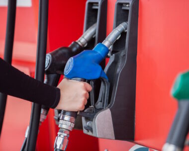 close up hand of woman holding pump nozzle for service at gas station. male employee worker fueling oil car. business energy concept.