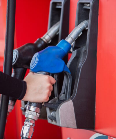 close up hand of woman holding pump nozzle for service at gas station. male employee worker fueling oil car. business energy concept.