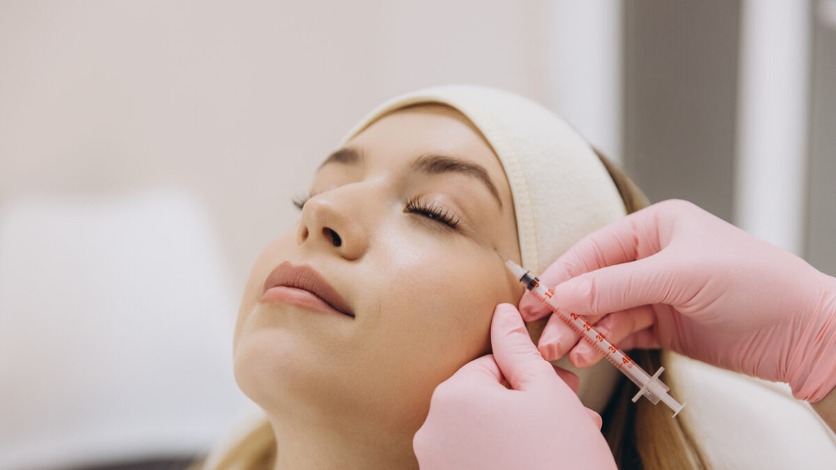 Skilled cosmetologist performing anti aging injection, treating patient's facial wrinkles during professional cosmetic procedure in clinic