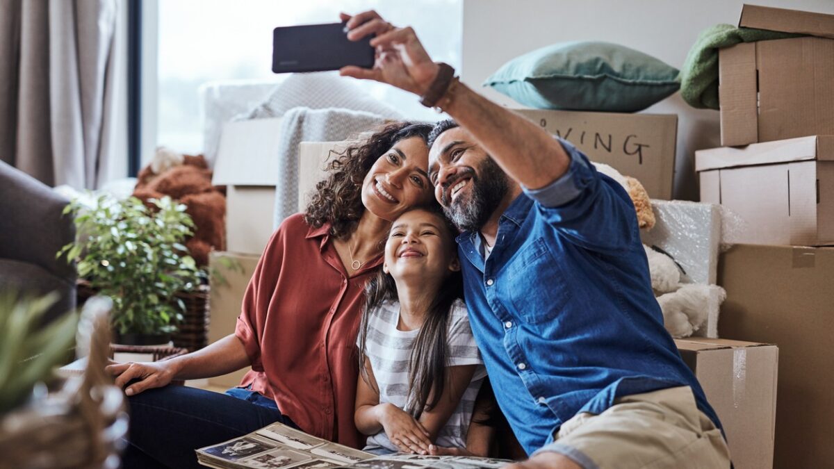 A joyful family captures a selfie while surrounded by boxes during their exciting moving day, celebrating new beginnings.