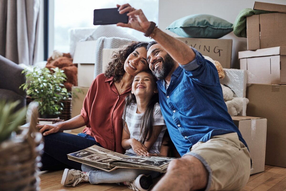 A joyful family captures a selfie while surrounded by boxes during their exciting moving day, celebrating new beginnings.
