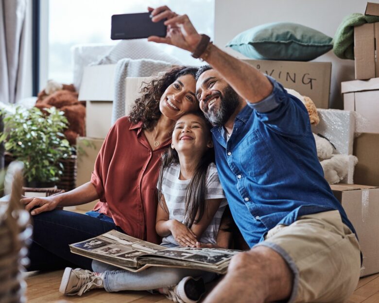 A joyful family captures a selfie while surrounded by boxes during their exciting moving day, celebrating new beginnings.