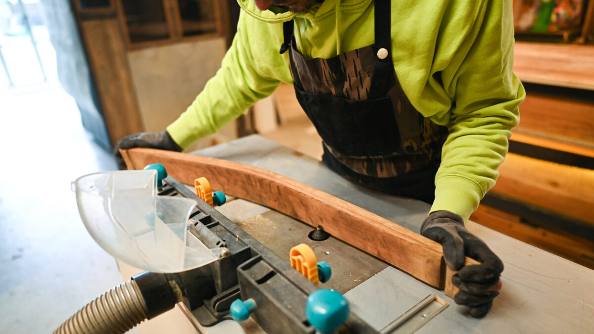 Carpenter using router table and vacuum dust collector for woodworking