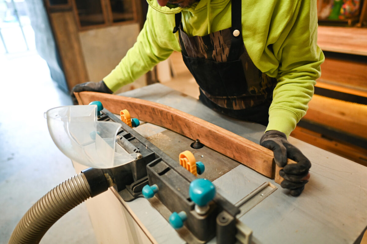 Carpenter using router table and vacuum dust collector for woodworking