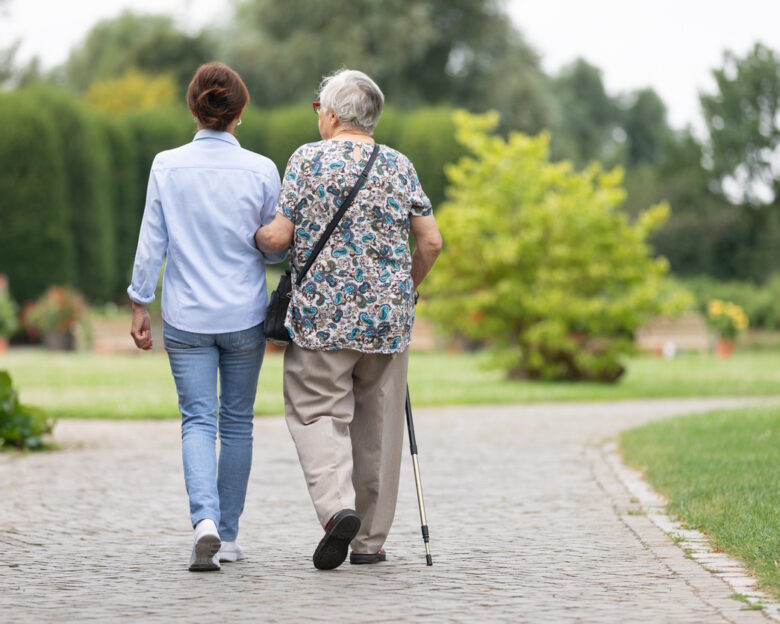 Happy senior woman and caregiver walking outdoors