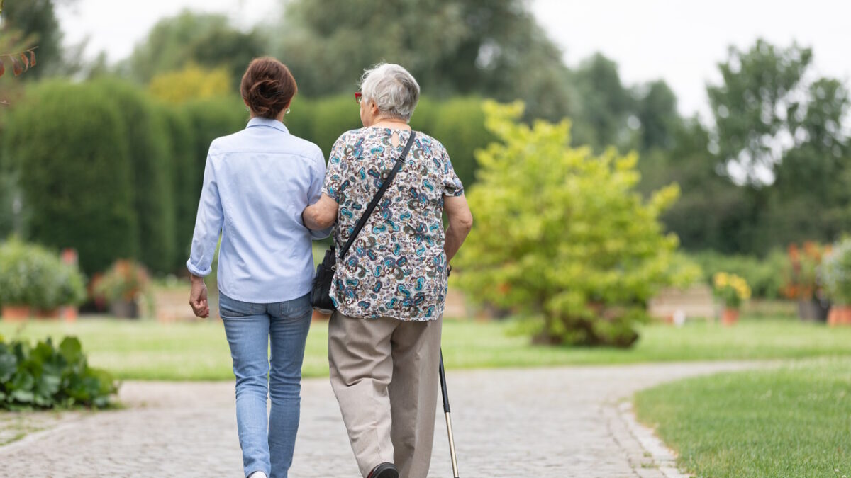Happy senior woman and caregiver walking outdoors
