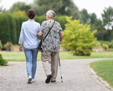 Happy senior woman and caregiver walking outdoors