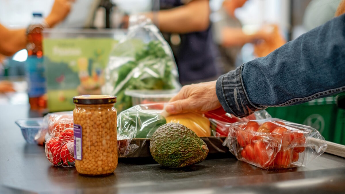 Senior caucasian woman putting goods on supermarket checkout conveyor belt, concept of shopping in grocery store, consumerism