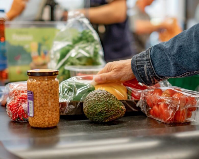 Senior caucasian woman putting goods on supermarket checkout conveyor belt, concept of shopping in grocery store, consumerism