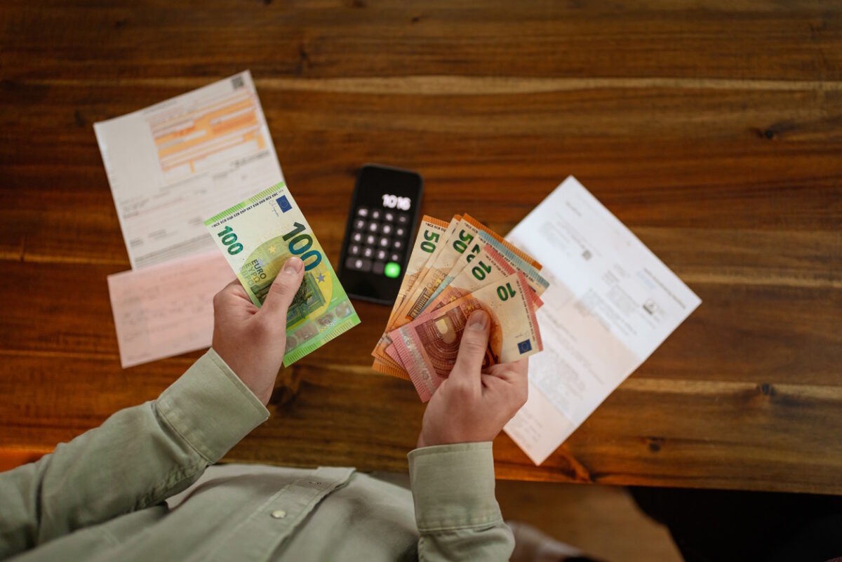 Close up of hands counting euro banknotes while planning household expenses and reviewing financial obligations