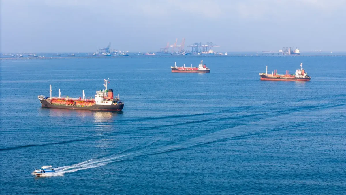 LPG gas and oil tanker ships anchored in the ocean, with a fast patrol boat in the foreground. Global energy transport, war energy crisis, and Strait of Hormuz blockade concept.