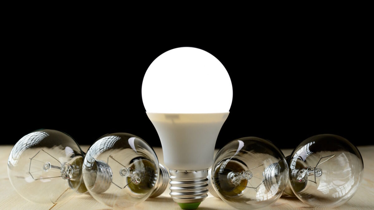 LED lamp standing on a wooden table, near an incandescent lamp lie