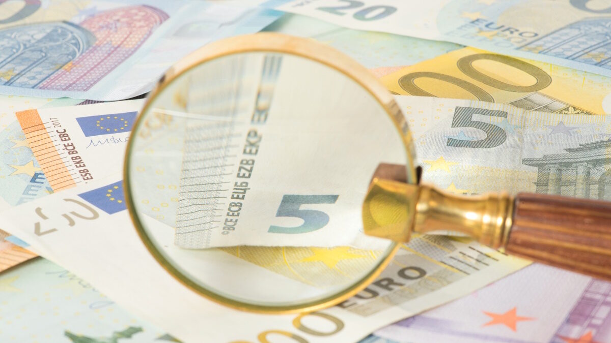 Euro banknotes and a magnifying glass