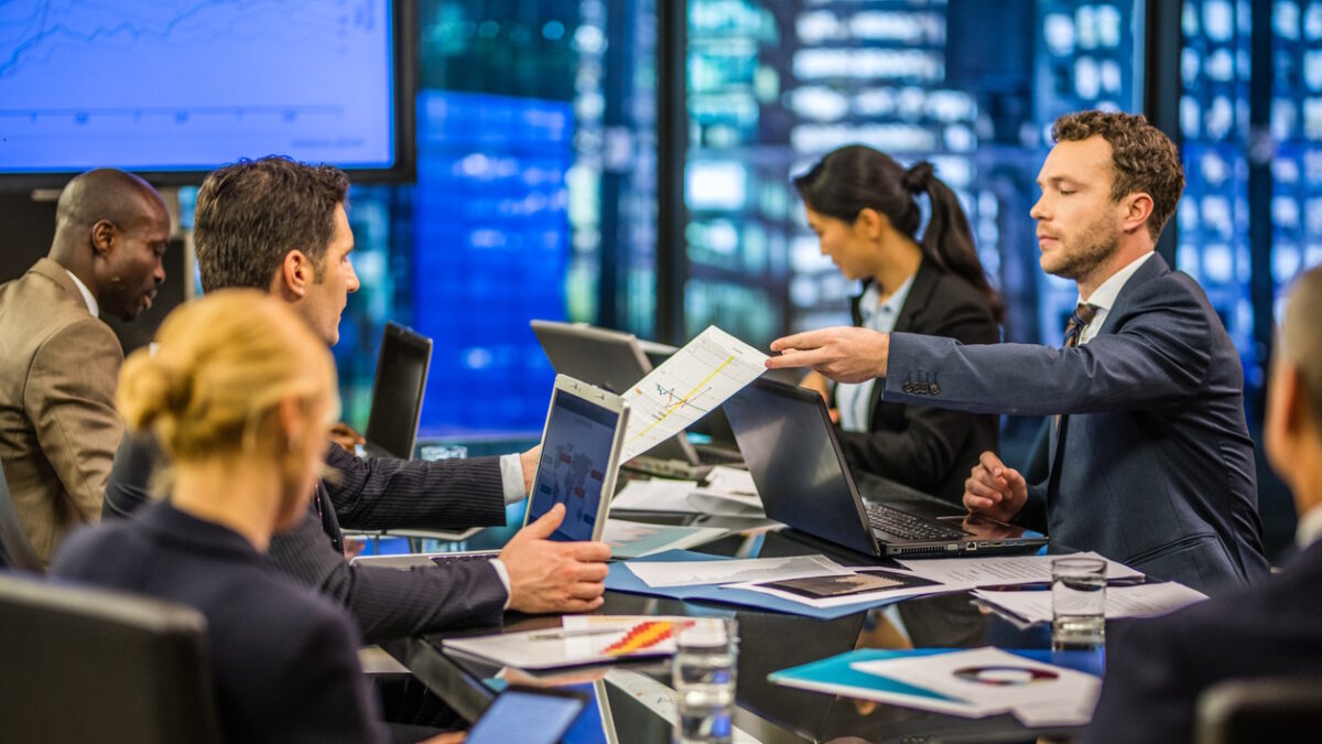 Business people working together, businessman showing document to another businessman in conference room.