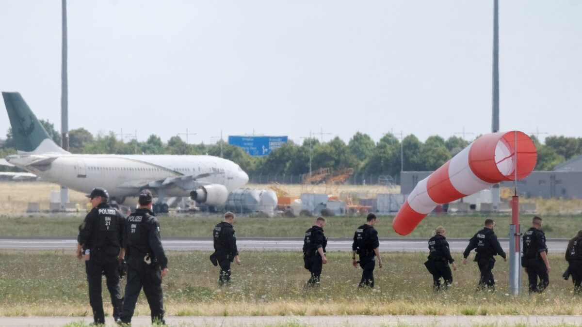07 August 2026, Saxony, Schkeuditz: Police officers are walking across a field on the grounds of Leipzig Airport. The investigation into the discovery of the explosive-laden drone is ongoing. Numerous police officers are on the scene near the northern runway, searching the area on foot.