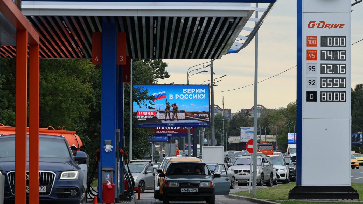 Cars queue to refuel at a Gazprom Neft fuel station amid fuel shortages following recent series of Ukrainian air attacks on oil refineries in Russian regions and further gasoline production cuts, in the course of the Russia-Ukraine conflict, in Moscow, Russia, August 20, 2026. The banner marking the upcoming National Flag Day reads: "We believe in Russia!" REUTERS