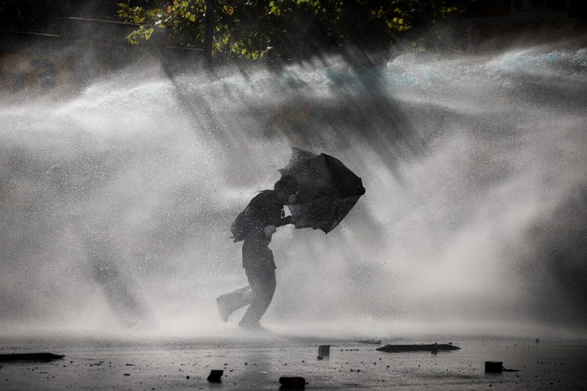 A demonstrator uses an umbrella to shield against water sprayed from a water cannon during an anti-government protest by students in Tirana, Albania, October 17, 2026. REUTERS