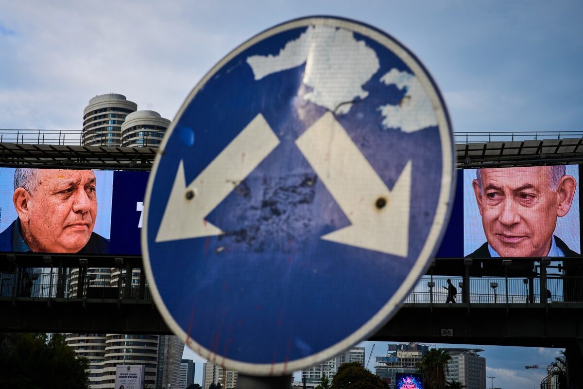 People cross a bridge beneath a television campaign advertisement featuring Israeli Prime Minister Benjamin Netanyahu, right, and his main rival, opposition candidate Gadi Eisenkot, ahead of Israel's general election in Ramat Gan, Israel, Sunday, Oct. 18, 2026. (AP Photo