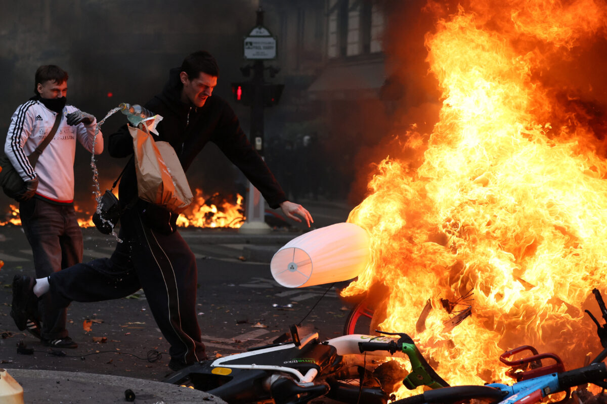 Masked protesters throw objects onto a burning barricade amid clashes during a day of demonstrations against the cost of living and rising fuel prices in Paris as part of nationwide protests called by the "Yellow Vests" movement, joined by French high school and university students, teachers and parents demanding better school conditions and government action, as well as labour unions, workers, farmers and retirees, France, October 17, 2026. REUTERS