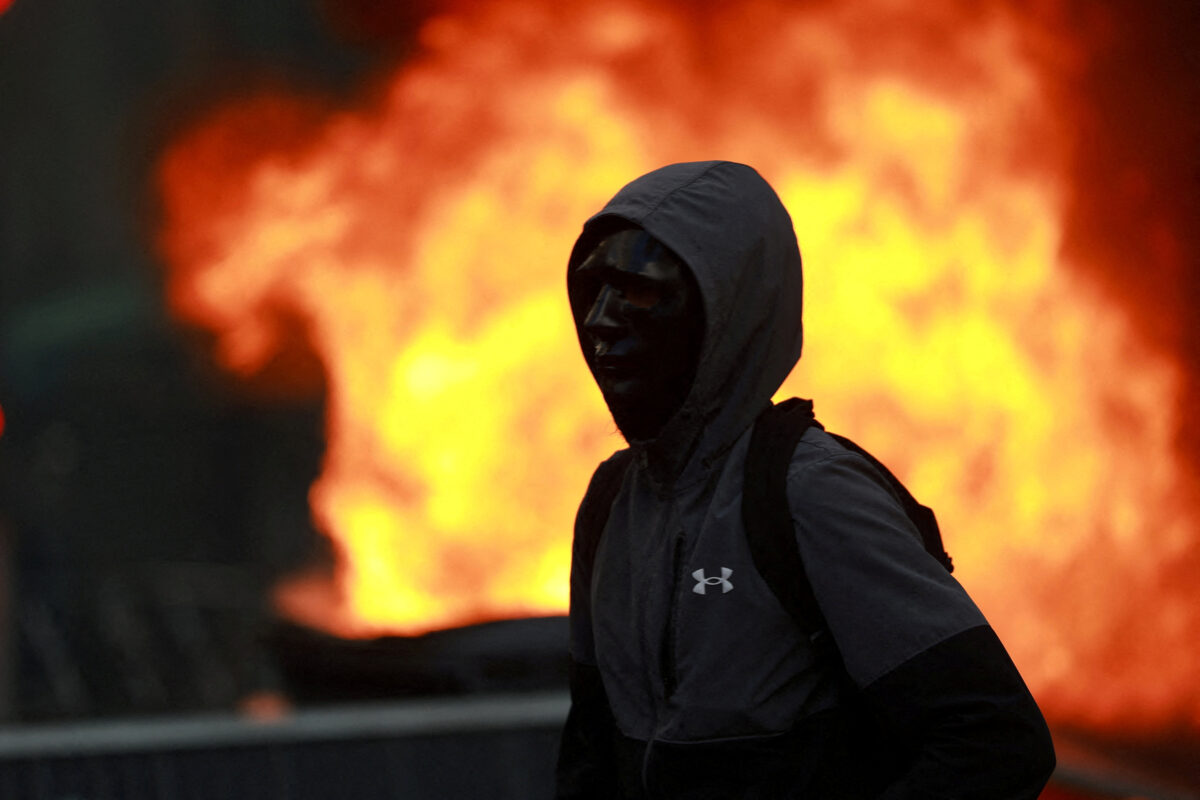 A masked protester stand next to burning garbage bin and other objects amid clashes during a demonstration against the cost of living and rising fuel prices in Paris as part of nationwide protests called by the "Yellow Vests" movement, joined by French high school and university students, teachers and parents demanding better school conditions and government action, as well as labour unions, workers, farmers and retirees, France, October 17, 2026.  REUTERS