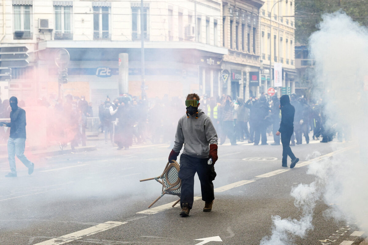 A protester, wearing a gas mask and protective eyewear, drags a chair amidst tear gas, during a demonstration banned by local authorities and called by the "Yellow Vests" movement, joined by French high school and university students, against the cost of living and rising fuel prices, in Lyon, France, October 24, 2026. REUTERS