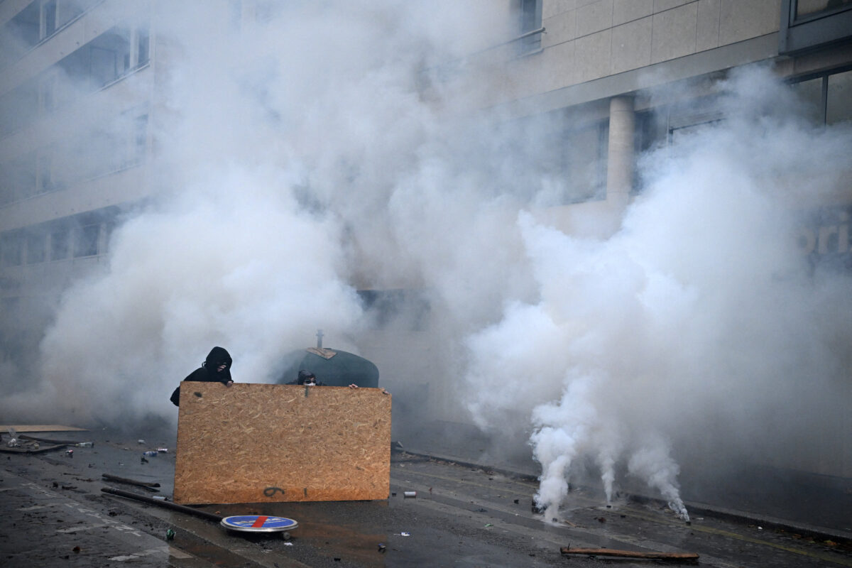 Masked protesters take cover behind a plywood board amid clashes and tear gas during an authorised demonstration organised by labour unions in Paris as part of nationwide protests called by the "Yellow Vests" movement joined by French high school and university students against the cost of living and rising fuel prices, in France, October 24, 2026. REUTERS