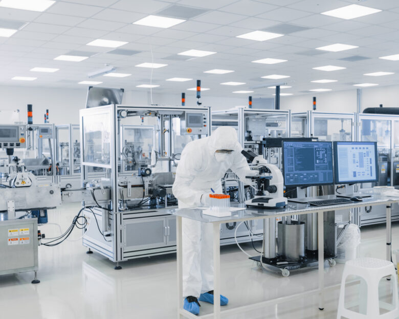 Shot of Sterile Pharmaceutical Manufacturing Laboratory where Scientists in Protective Coverall's Do Research, Quality Control and Work on the Discovery of new Medicine.