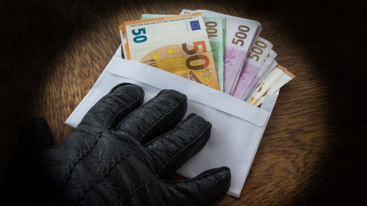 Hand in a Black Glove Handing Over an Envelope with a Bribe or Dirty Money