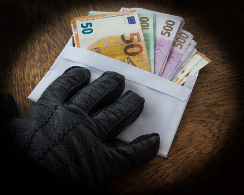Hand in a Black Glove Handing Over an Envelope with a Bribe or Dirty Money