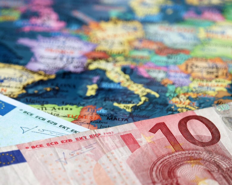 Euro banknotes on the map of Europe, selective focus. Concept for european economy, eurozone countries