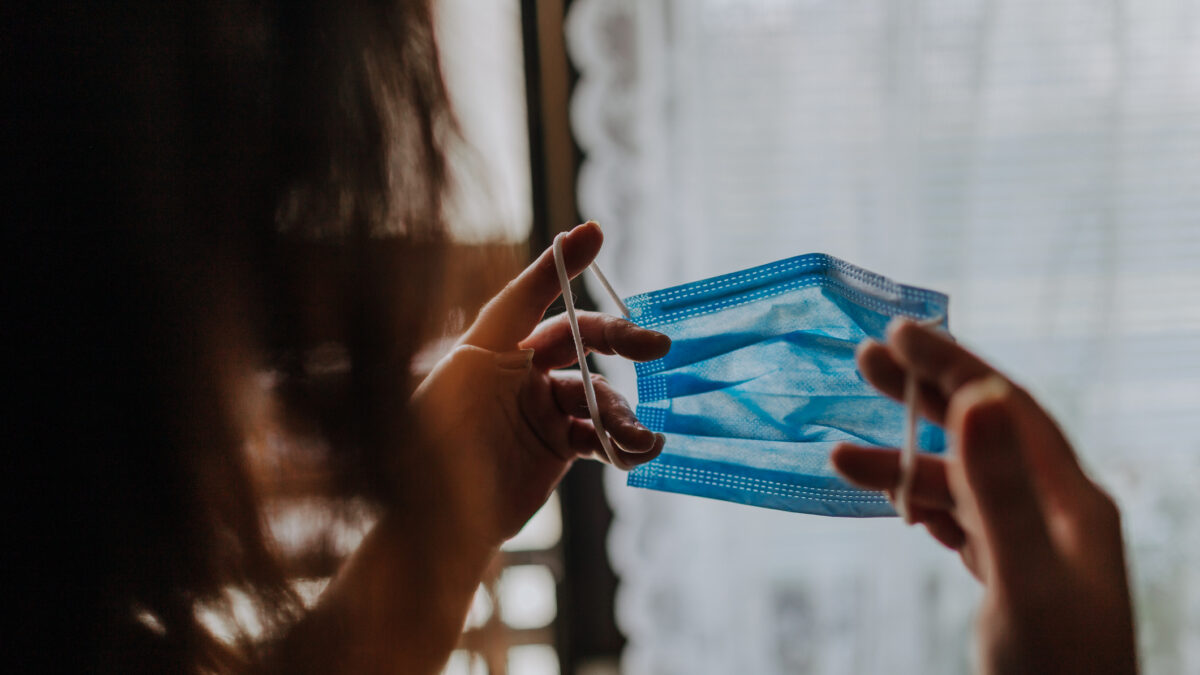 Woman is holding a COVID-19 anti-coronavirus mask as protection against infection