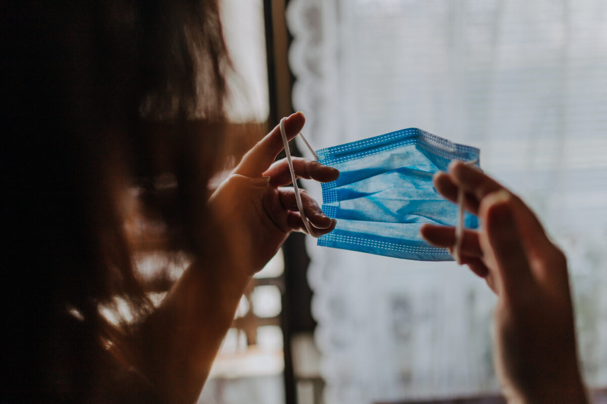 Woman is holding a COVID-19 anti-coronavirus mask as protection against infection