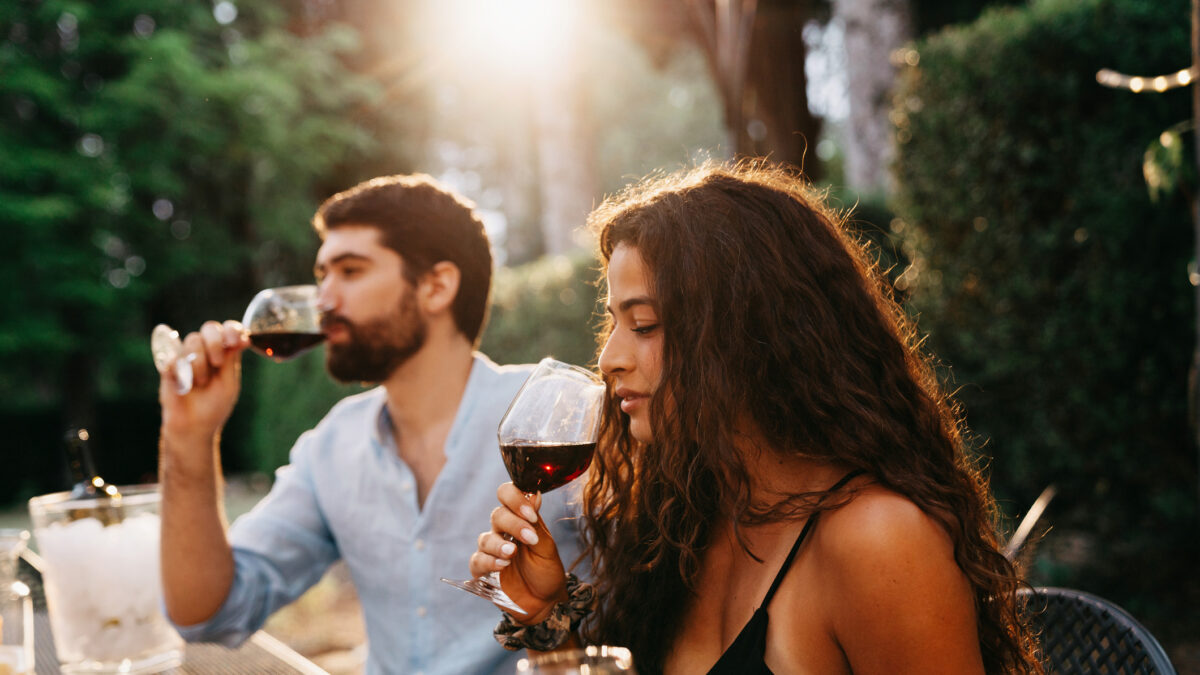 People are having a wine tasting experience at the farmhouse. Sunset time. Friends on vacation together.