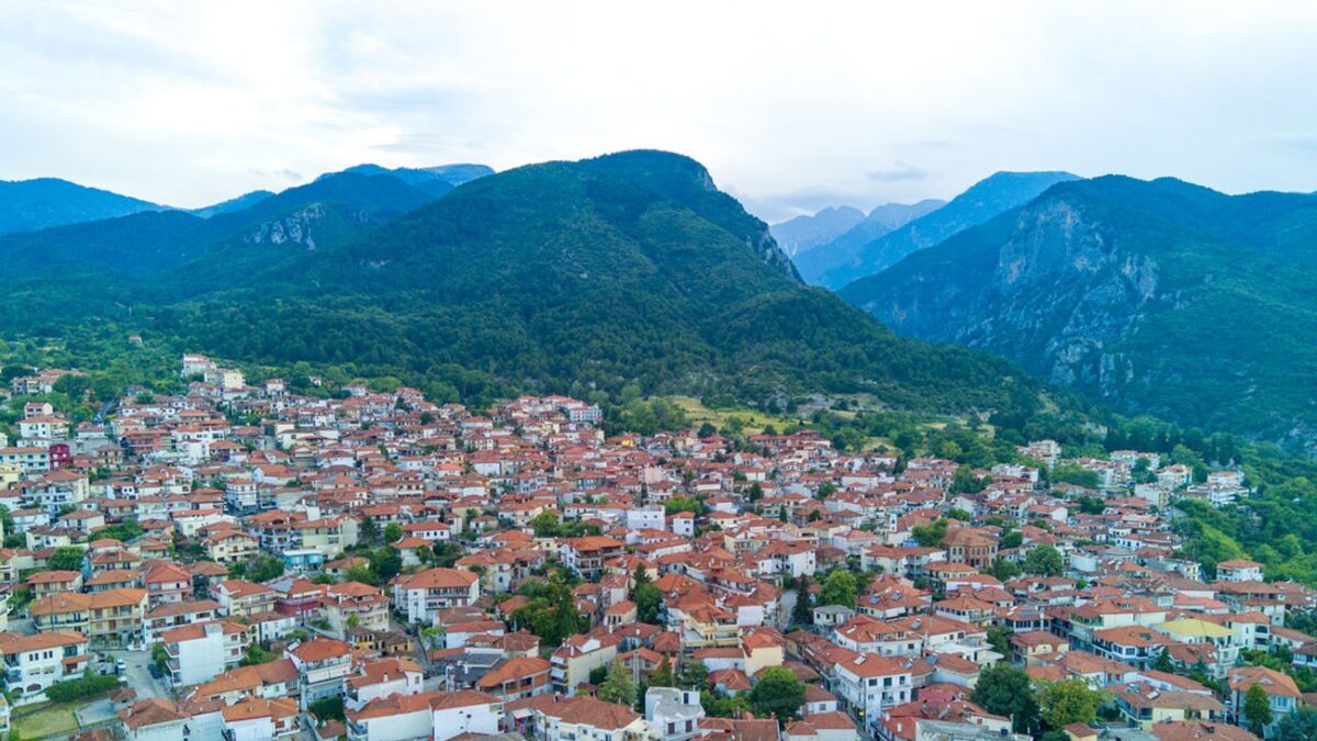 Small Greek quiet resort town of Litochoro with small houses with red tiled roofs and narrow empty streets against the backdrop of the majestic famous high Mount Olympus and a cloudy sky