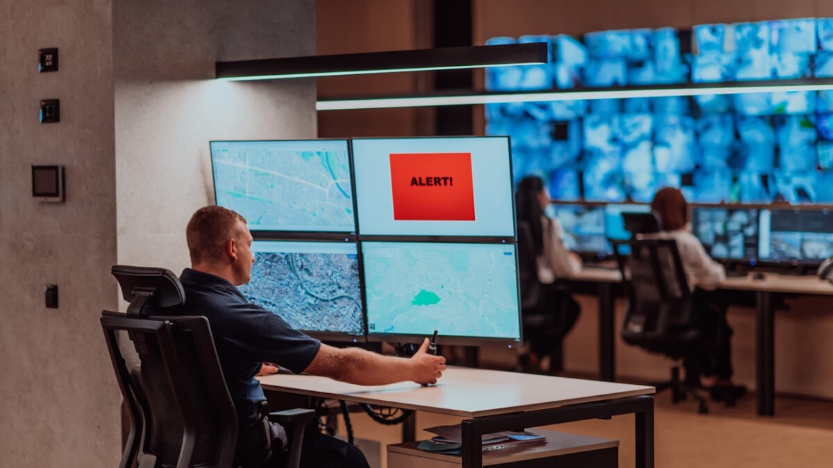 Group of Security data center operators working in a CCTV monitoring room looking on multiple monitors.Officers Monitoring Multiple Screens for Suspicious Activities.