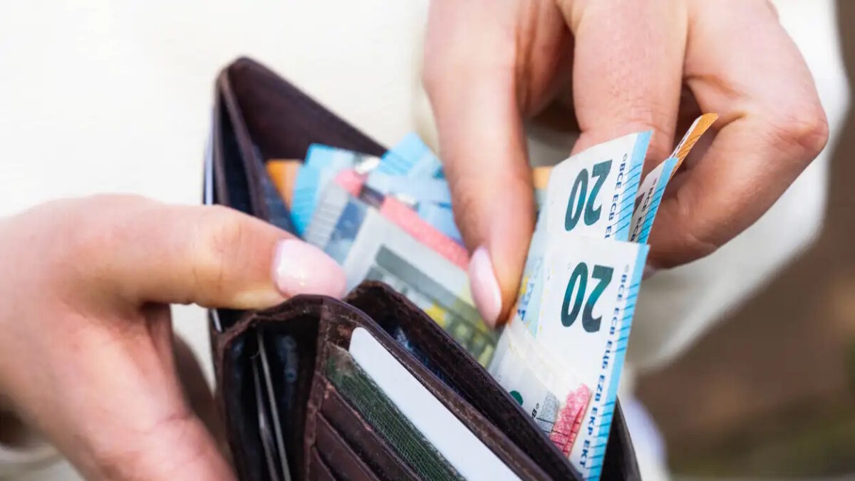 Macro image as a woman takes Euro banknotes from a leather wallet.