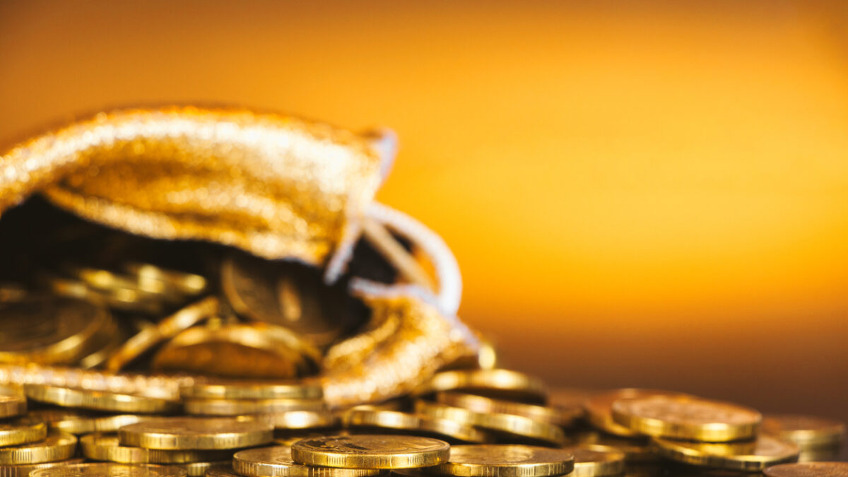 Gold coins in sack. Gold money on orange background. Copy space. A pile of coins. A bag with gold coins. Treasure hunt