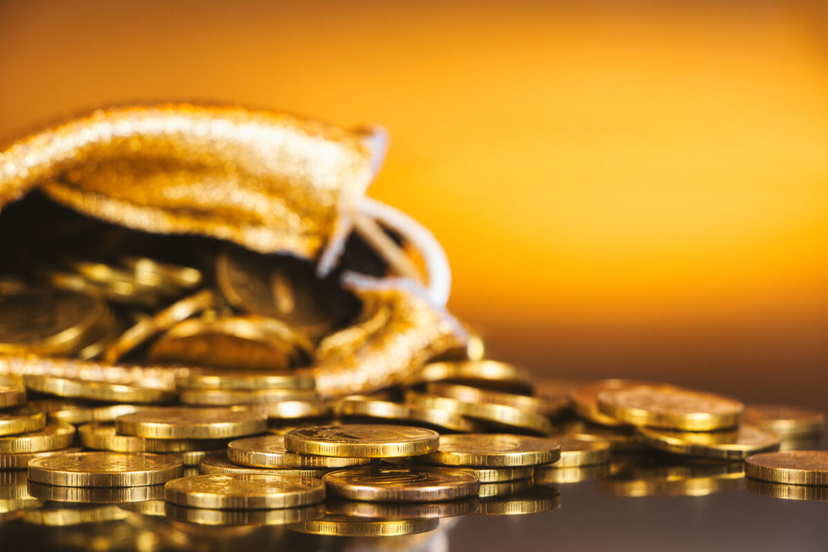 Gold coins in sack. Gold money on orange background. Copy space. A pile of coins. A bag with gold coins. Treasure hunt