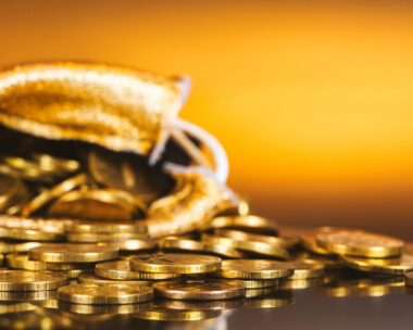 Gold coins in sack. Gold money on orange background. Copy space. A pile of coins. A bag with gold coins. Treasure hunt