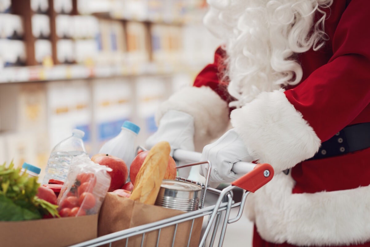 Santa Claus doing grocery shopping at the supermarket, he is pushing a full shopping cart, hands close up