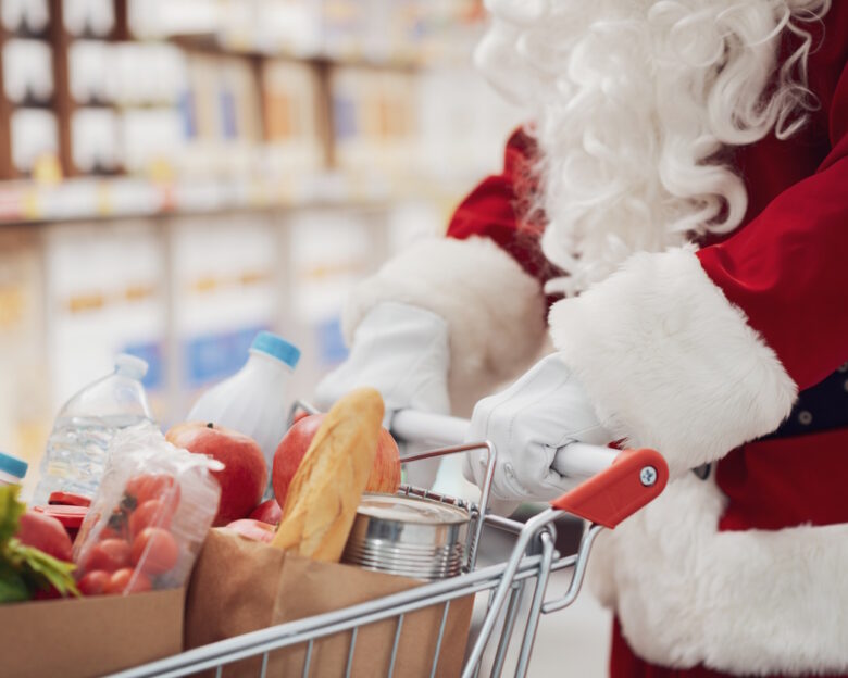 Santa Claus doing grocery shopping at the supermarket, he is pushing a full shopping cart, hands close up