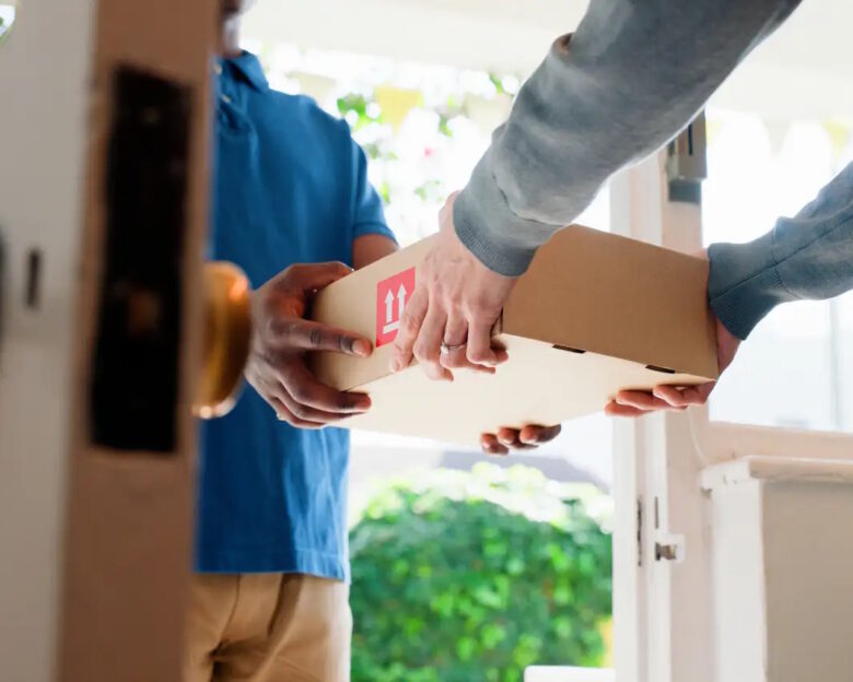 Hands, box and delivery man at front door in home with client, services and shipping for commercial product
