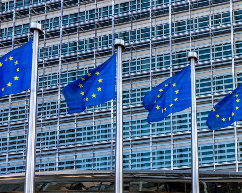 Four European flags, symbols of the European Union (EU), fluttering against the Berlaymont building, headquarters of the European Commission in Brussels, Belgium