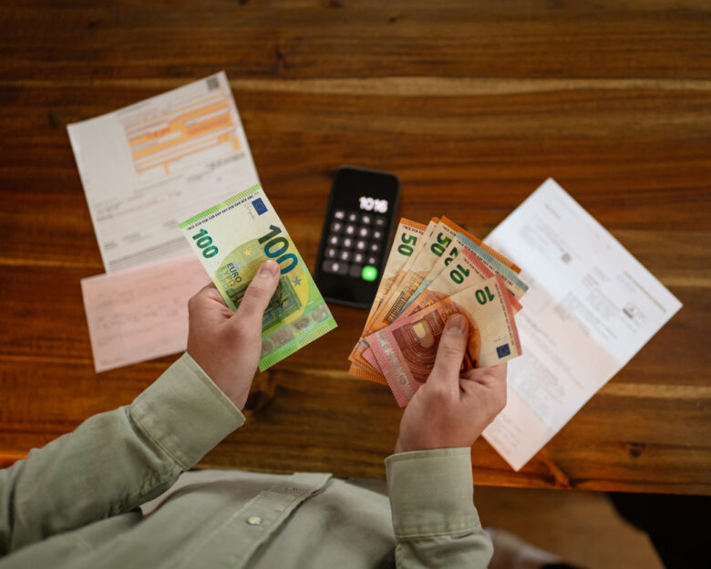 Close up of hands counting euro banknotes while planning household expenses and reviewing financial obligations