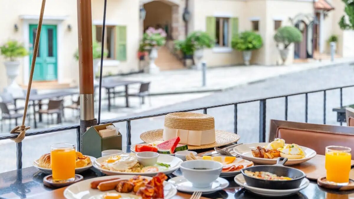 Breakfast table served with eggs, juice and fruit on an outdoor terrace overlooking a cobblestone street. Luxury travel lifestyle and morning dining in a European style village.