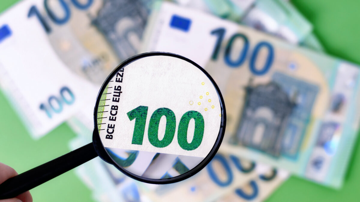 Black magnifying glass checking authenticity of 100 euro banknote