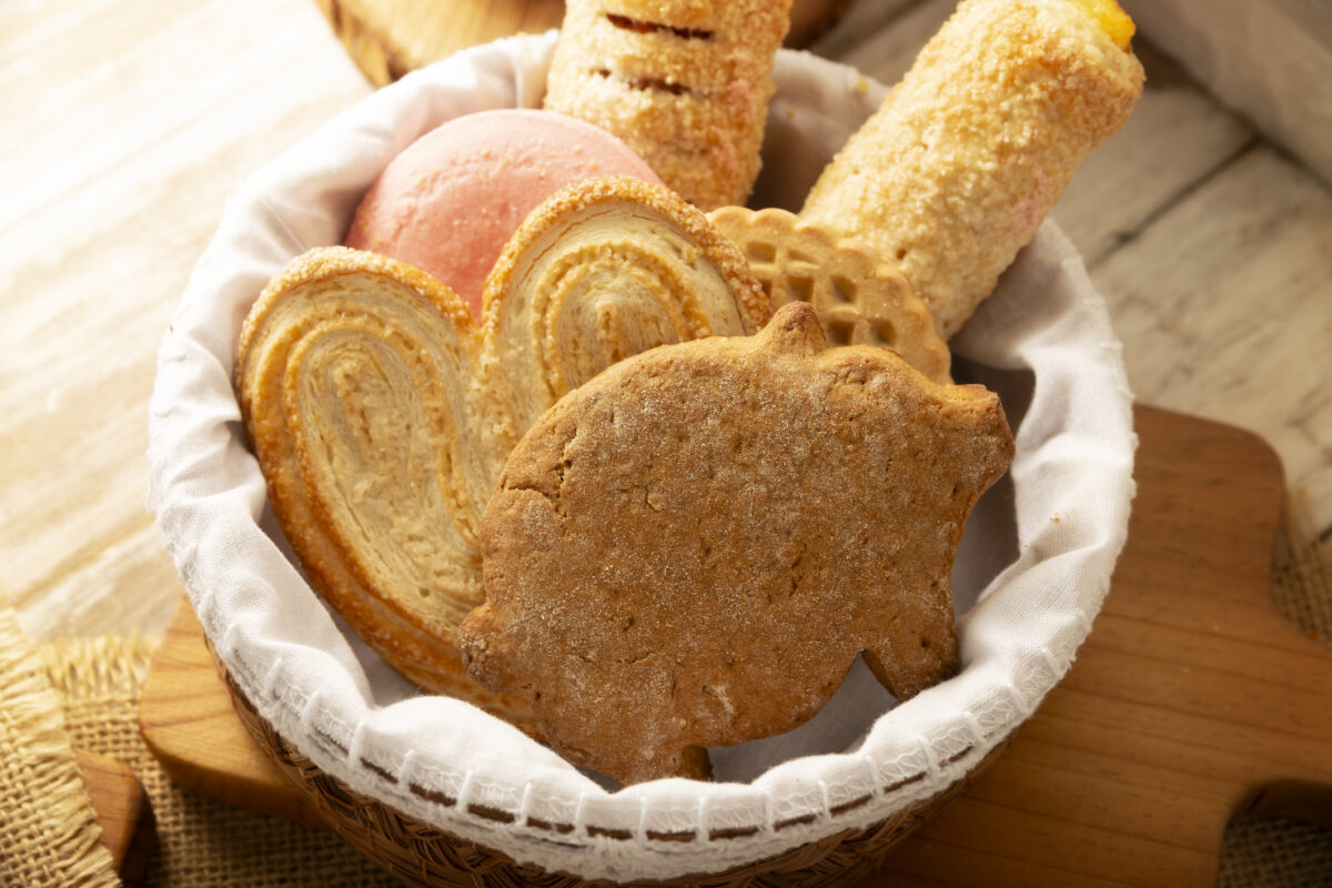Traditional Mexican sweet breads, marranito de piloncillo, polvorón, and oreja served in a cloth-lined basket.